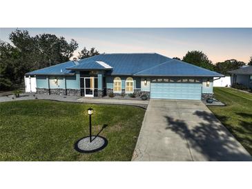 Single-story home with metal roof, light blue siding, and landscaped lawn at 7435 Snow Dr, Englewood, FL 34224