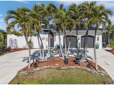 White house with palm trees, circular driveway, and two-car garage at 1454 Kiwi Ct, Punta Gorda, FL 33950