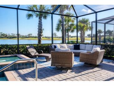 Relaxing lanai with wicker furniture and spa overlooking a lake at 25228 Longmeadow Dr, Punta Gorda, FL 33955