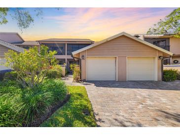 Inviting exterior view showcasing the home's two-car garage and landscaped front yard with a brick paved driveway at 5220 Landings Blvd # 104, Sarasota, FL 34231