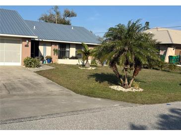 Ranch-style home with metal roof, landscaped yard, and driveway at 1311 Abscott St, Port Charlotte, FL 33952