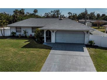 Charming single-story home featuring a two-car garage, well-maintained lawn, and beautiful landscaping at 20431 Calder Ave, Port Charlotte, FL 33954