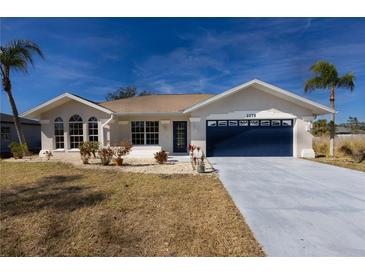 Charming single-Gathering home features a well-maintained lawn and a stylish blue garage door at 2275 Logsdon St, North Port, FL 34287