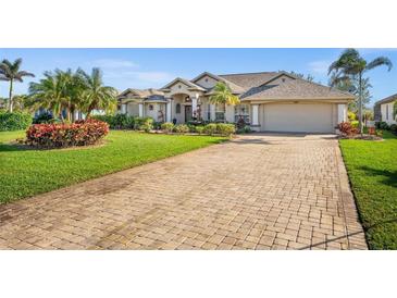 Beautiful single Gathering home with a brick driveway, manicured lawn, and lush tropical landscaping at 290 Rotonda E Blvd, Rotonda West, FL 33947