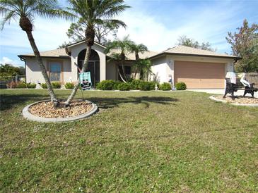 Charming home featuring a two-car garage, well-manicured lawn, and decorative landscaping with palm trees at 1247 Petronia St, North Port, FL 34286