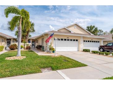 Inviting home featuring an attached garage, lush lawn, and mature palm trees at 1706 Fountain View Cir, Venice, FL 34292