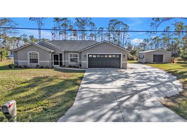 Charming single story house with gray exterior, attached garage, and long concrete driveway at 4175 Horseshoe Ave, North Port, FL 34286