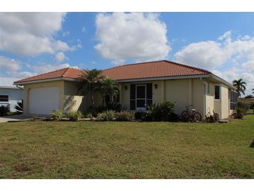 Charming single-story home featuring a red tile roof, well-maintained lawn, and mature landscaping at 1727 Boca Raton Ct, Punta Gorda, FL 33950