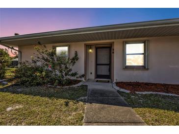 Charming home featuring a cozy front entrance, with beautiful flowering plants and a well-kept lawn at 25068 Harborview Rd # 3B, Punta Gorda, FL 33980