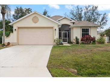 Charming one-story home with attached two-car garage, well-maintained lawn, and tropical landscaping at 2621 San Maria Cir, North Port, FL 34286