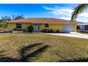 Charming one-story yellow home with a well-manicured lawn and driveway leading to an attached garage at 8029 Roy Dr, Punta Gorda, FL 33982