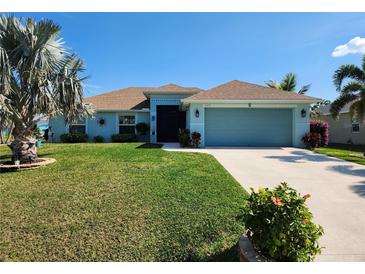 Charming single-story home with a well-manicured lawn, palm trees, and a two-car garage, showcasing curb appeal at 9175 Melody Cir, Port Charlotte, FL 33981