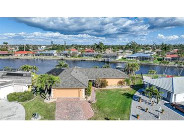 Waterfront home with a tile roof, attached garage, and tropical landscaping, located on a canal with boat access at 1200 Winward Ct, Punta Gorda, FL 33950