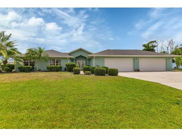 Charming single-story home with a spacious lawn, manicured bushes, and a three car garage at 23411 Superior Ave, Port Charlotte, FL 33954