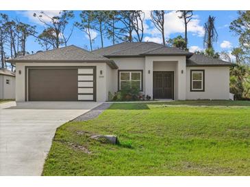 Beautiful single-story home with a modern facade, well-manicured lawn, and a two-car garage at 3049 Seth Rd, North Port, FL 34288