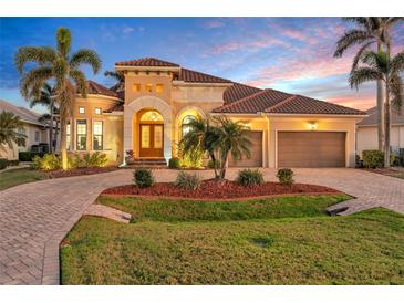 Stunning home exterior with tropical landscaping, barrel tile roof, and brick paved driveway at 3321 Tripoli Blvd, Punta Gorda, FL 33950