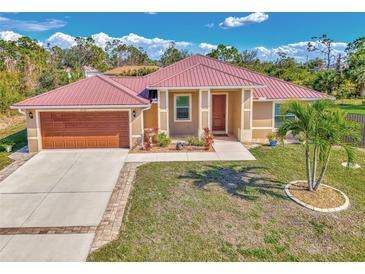 Charming single-story home featuring a metal roof, well-manicured lawn, and attached two-car garage at 8230 Agate St, Port Charlotte, FL 33981