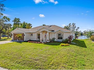 Charming single-story home featuring a well-maintained lawn, colorful landscaping, and an attached two-car garage at 1391 Abalom St, Punta Gorda, FL 33980