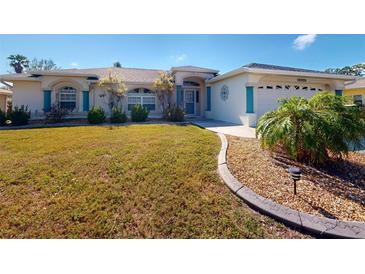 Well-maintained front yard featuring green grass, decorative rock garden, and charming exterior details at 18335 Lamont Ave, Port Charlotte, FL 33948