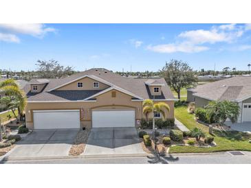Charming tan two-story home featuring a well-manicured lawn and a spacious two-car garage at 24036 Buckingham Way, Port Charlotte, FL 33980