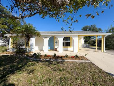 Charming home featuring white exterior with colorful blue door and yellow trim details at 13468 Romford Ave, Port Charlotte, FL 33981