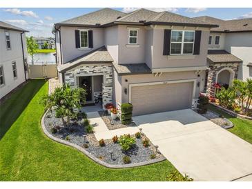 Two-story house with stone accents and landscaped yard at 7537 Pool Compass Loop, Wesley Chapel, FL 33545