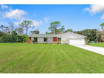 Single-story home with green roof, white exterior, and spacious lawn at 1115 Larchmont Dr, Englewood, FL 34223