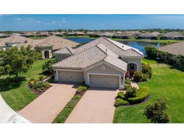 Luxury home with three-car garage, manicured lawn, and lake view at 1384 Backspin Dr, Englewood, FL 34223