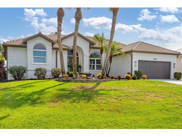 Charming single-story home boasts a beautifully landscaped front yard with lush green grass and palm trees at 4663 Arlington Dr, Placida, FL 33946