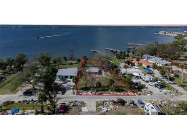 Aerial view of waterfront lot, neighboring houses, and nearby debris at 128 Winson Ave, Englewood, FL 34223