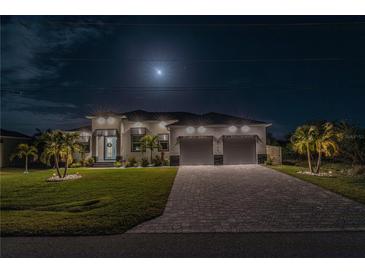 Night view of home's front exterior, showcasing a well-lit facade, two-car garage and a paver driveway at 8198 Clyde Cir, Port Charlotte, FL 33981