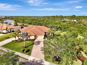 Aerial view of single-story home with tile roof, driveway, and lush landscaping at 13241 Creekside Ln, Port Charlotte, FL 33953