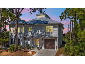 Two-story house with gray siding, metal roof, and a two-car garage at 7064 Baypine Ln, Englewood, FL 34224