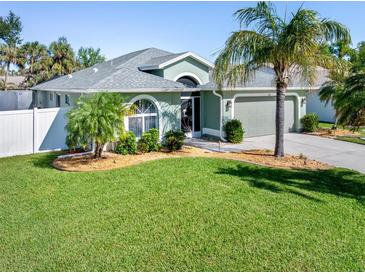 Single-story house with a green exterior, landscaping, and palm trees at 126 Spur Dr, Rotonda West, FL 33947