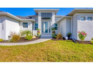 White modern home with gray roof, walkway, and landscaped lawn at 14252 Joggins Ave, Port Charlotte, FL 33981