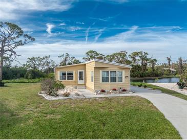 Tan mobile home with landscaped yard and waterfront view at 3302 Bluejay Ln, Englewood, FL 34224