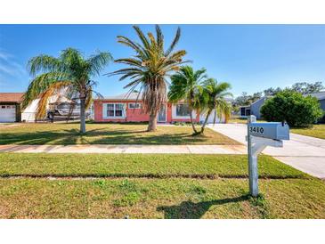 Pink house with palm trees and a well-maintained lawn at 3460 Lullaby Rd, North Port, FL 34287