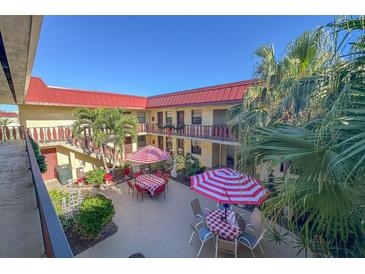 Community courtyard with tables, umbrellas, and tropical landscaping at 66 Boundary Blvd # 271, Rotonda West, FL 33947