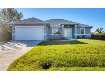 Newly constructed home with gray exterior, two-car garage, and well-manicured lawn at 119 White Pine Dr, Rotonda West, FL 33947