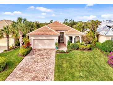 Single-story home with tile roof, landscaped yard, and brick paver driveway at 13376 Creekside Ln, Port Charlotte, FL 33953