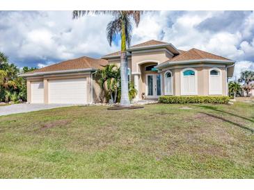 Tan house with three-car garage, palm trees, and landscaped lawn at 17164 Canary Ln, Port Charlotte, FL 33948