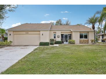 Tan house with a stone accent, screened entry, and landscaped lawn at 2365 Malaya Ct, Punta Gorda, FL 33983