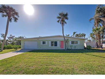 Light green single story home with pink door, white garage door, and palm trees at 701 W Perry St, Englewood, FL 34223