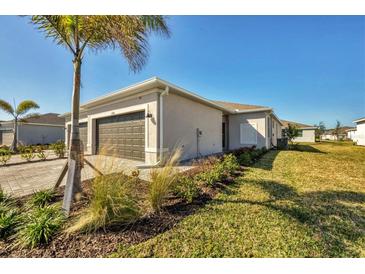 Single-story home with two-car garage and landscaped lawn at 8746 Saint Kitts Cir, Englewood, FL 34224