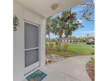 Inviting condo entryway with screen door, showcasing a well-maintained walkway and landscaping at 1 Quails Run Blvd # 5, Englewood, FL 34223