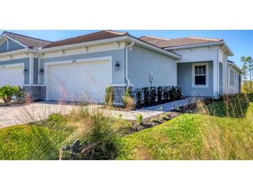 Light blue two-car garage home with walkway, landscaping, and driveway at 11243 Boundless Ter, Venice, FL 34293