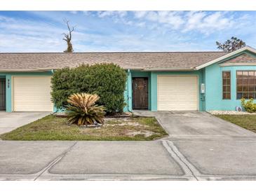 Light teal exterior of home with attached garage and landscaping at 255 Boundary Blvd # 104, Rotonda West, FL 33947