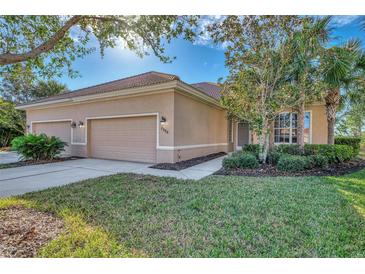 Tan house with three-car garage, lush landscaping, and walkway at 2888 Myakka Creek Ct., Port Charlotte, FL 33953