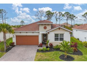 One-story home with orange garage door, landscaping, and paver driveway at 305 Daylily Blvd, Nokomis, FL 34275