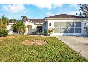 Single-story home with a two-car garage and well-manicured lawn at 6256 Pennell St, Englewood, FL 34224